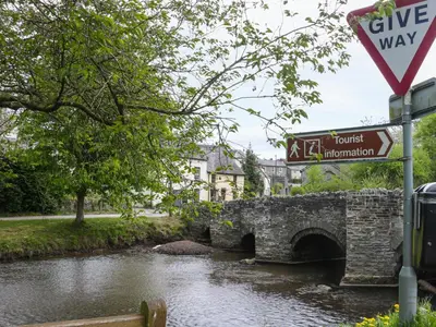 a stone bridge over a river with a street sign at Castle Cottage in Clun