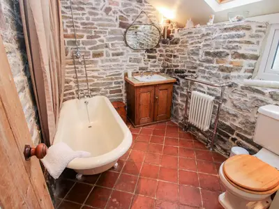 a bathroom with a tub and a toilet and a sink at Castle Cottage in Clun
