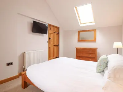 a bedroom with a white bed and a tv on the wall at Ty Gwyn in Llangwm