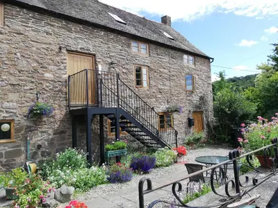 a stone house with a staircase and flowers in front of it at The Gallery in Craven Arms