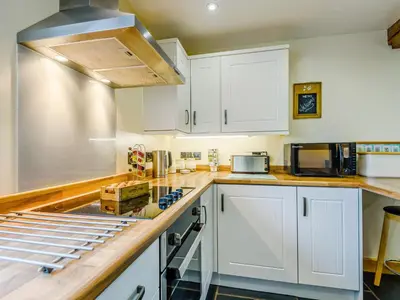 a kitchen with white cabinets and a stove top oven at The Stables in Llanfair Caereinion