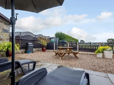 a patio with a picnic table and an umbrella at The Stables in Llanfair Caereinion