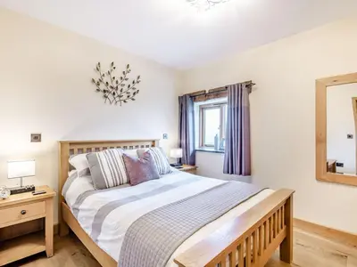 a bedroom with a large bed and a mirror at The Granary in Llanfair Caereinion