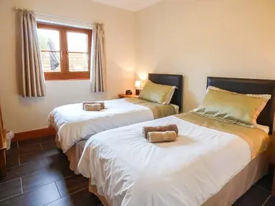 two beds in a room with a window at Y Bwthyn in Ystrad Meurig