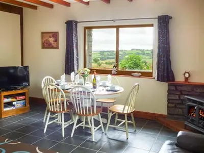 a dining room with a table and chairs and a window at Y Bwthyn in Ystrad Meurig