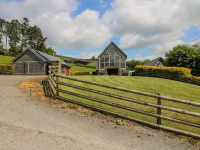 a farm house with a fence and a field at The Hayloft in Knighton