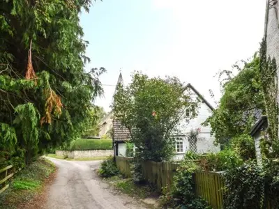 a dirt road next to a house with a fence at The Smithy in Leominster