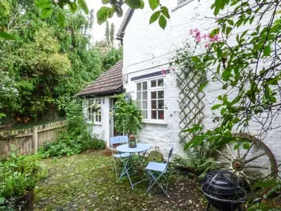 a small white house with a table and chairs in the yard at The Smithy in Leominster