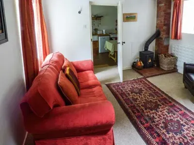 a red couch in a living room with a fireplace at The Smithy in Leominster