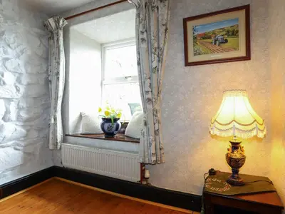 a lamp on a table in a room with a window at Hendy Cottage in Llanbedr