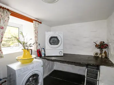 a kitchen with a washing machine and a microwave at Hendy Cottage in Llanbedr