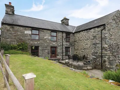 an old stone house with a yard in front of it at Hendy Cottage in Llanbedr