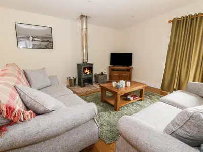 a living room with two couches and a wood stove at Y Felin - Moana in Borth