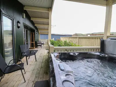 a large hot tub on a patio with chairs at Y Felin - Moana in Borth