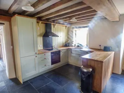 a kitchen with white cabinets and a wooden counter top at Tyn Llwyn in Dolgellau