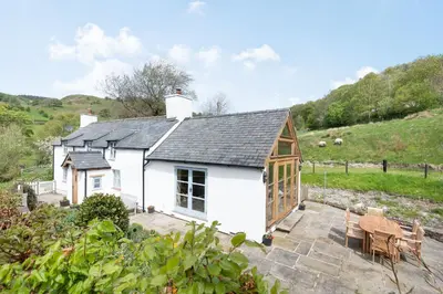 a white cottage with a table and chairs at Pen Y Bont in Llangollen