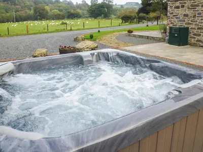 a hot tub filled with water in a yard at Tynddol Barn in Llanbadarn-fynydd