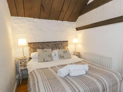 a bedroom with a large bed with two pillows at The Corn Store in Corwen