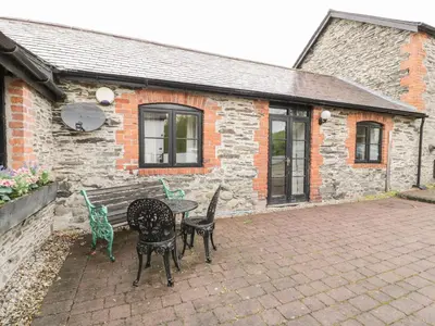 a patio with a table and chairs in front of a building at The Dairy in Corwen