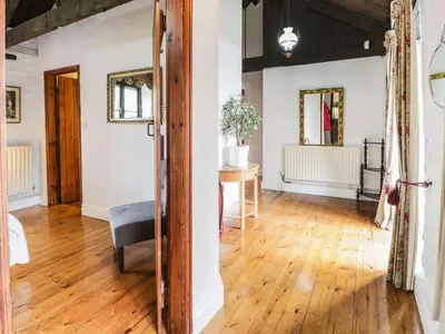 a living room with a wooden floor and a chair at The Dairy in Corwen