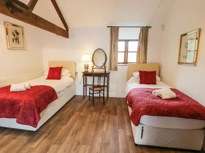 two beds in a room with a table and a mirror at The Dairy in Corwen