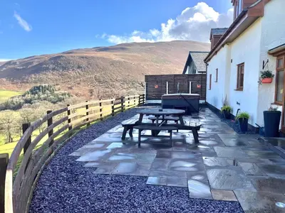 a picnic table on a stone patio with a hill in the background at Tyn Llwyn in Llangollen