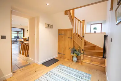 a hallway with a staircase and a living room at Tyn Llwyn in Llangollen