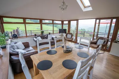 a living room with a wooden table and chairs at Tyn Llwyn in Llangollen
