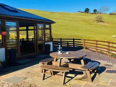 a picnic table and benches in front of a building at Tyn Llwyn in Llangollen