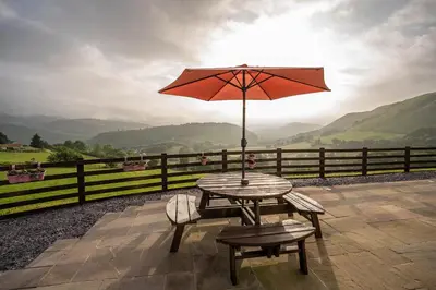 a table and chairs with an umbrella on a patio at Tyn Llwyn in Llangollen