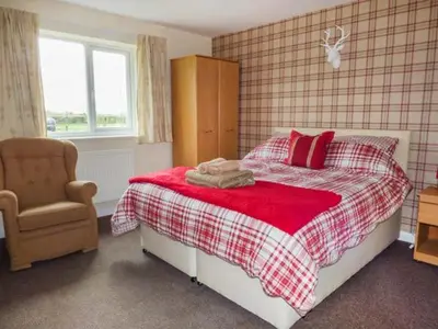 a bedroom with a bed with red pillows and a chair at The Willows in Ellesmere