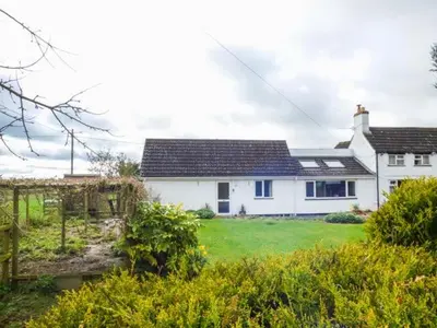 a white house with a black roof and a yard at The Willows in Ellesmere