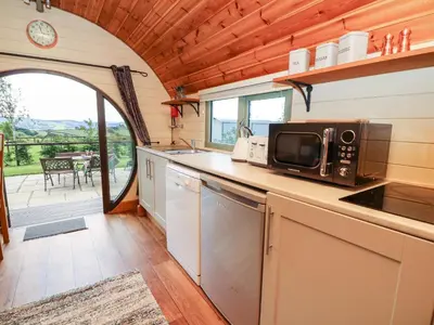 a kitchen with a microwave and a table with a patio at Meadow View in Saint Harmon