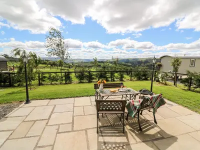 a table and chairs on a patio with a view at Meadow View in Saint Harmon