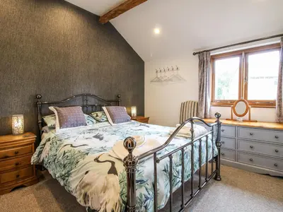 a bedroom with a bed and a dresser and a window at The Hay Loft in Craven Arms