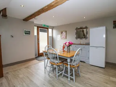 a kitchen with a table and chairs and a refrigerator at The Hay Loft in Craven Arms