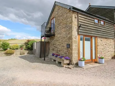 a stone house with a bench outside of it at The Hay Loft in Craven Arms