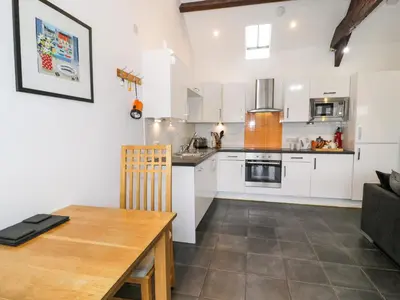 a kitchen with white cabinets and a wooden table at Bwthyn Bach in Llanddwywe