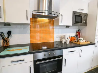 a kitchen with white cabinets and a stove top oven at Bwthyn Bach in Llanddwywe