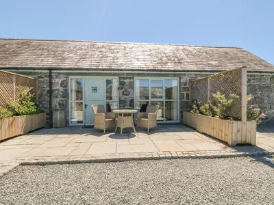 a patio of a cottage with a table and chairs at Bwthyn Bach in Llanddwywe