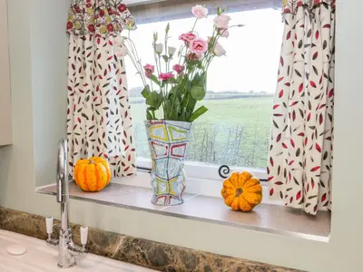 a window sill with a vase of flowers and pumpkins at Swallow Barn in Walford