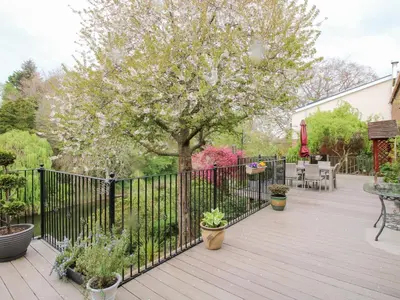 a wooden deck with a black fence and some plants at Riverdale in Shrewsbury