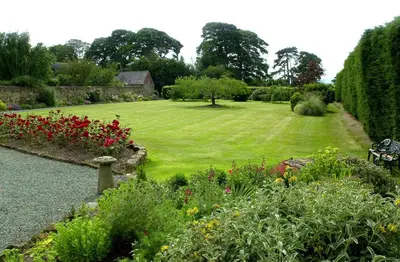 a garden with a green lawn and flowers at Hordley Hall in Ellesmere