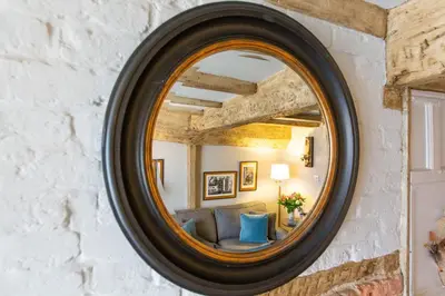 a mirror on a wall with a couch in a room at Charlie's Cottage in Ludlow