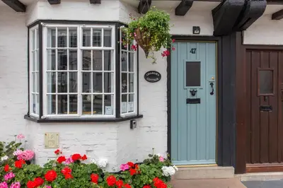 a house with a blue door and flowers at Charlie's Cottage in Ludlow