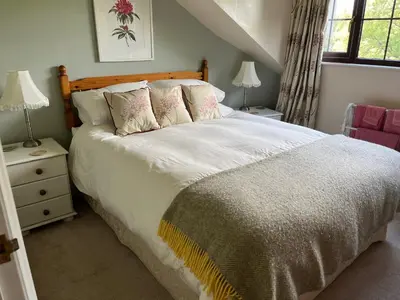 a bedroom with a large bed with white sheets and pillows at Kilsby Cottage in Llanwrtyd Wells