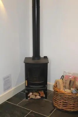 a black stove in a room with a basket at Capel- Y-Bryniau in Pennal