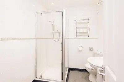 a white bathroom with a shower and a toilet at Elan Hotel in Rhayader