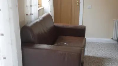 a brown leather couch in a room with a window at The Keep in Ludlow