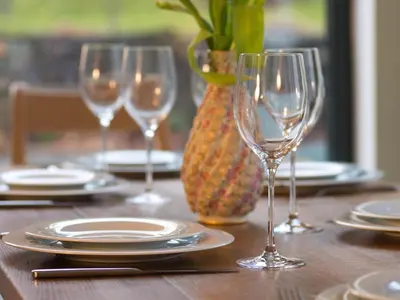 a wooden table with wine glasses and plates on it at Chapel House Cottage in Builth Wells
